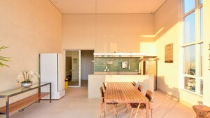 Una cocina moderna con salpicadero de azulejos, un comedor con mesa y sillas de madera, y vistas a la ciudad a través de amplios ventanales.