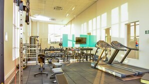Un gimnasio con cintas de correr, máquinas de pesas y pesas libres.