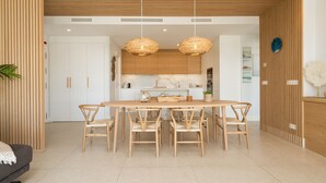 Une cuisine moderne avec une table et des chaises en bois, des luminaires suspendus et un meuble blanc.