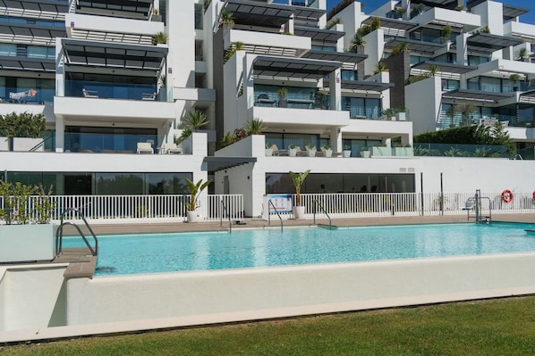Un edificio moderno con piscina, balcones y zonas de estar al aire libre.