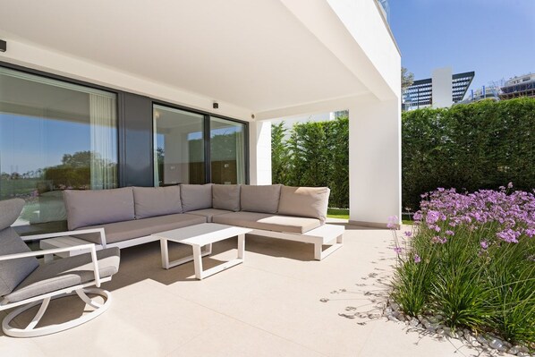 Un espacio exterior moderno con un sofá modular, una mesa baja y una mesa de comedor.