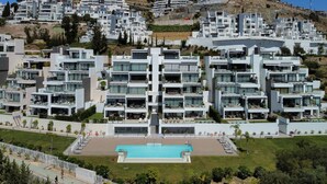 Un complexe résidentiel moderne comprenant plusieurs immeubles d’appartements, une piscine centrale et une pelouse bien entretenue.