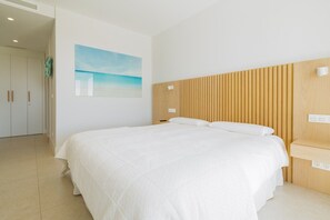 A hotel room with a large bed, a wooden headboard, a wall-mounted artwork, and a bedside table. - Aqualina de Madeira (Benahavís)