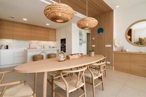 Una cocina moderna con armarios de madera, encimera de mármol y una mesa redonda con sillas de mimbre.