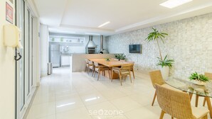 A modern kitchen with a dining area, featuring a large island, built-in appliances, and a flat-screen TV. - Incredible Stay With Pool and gym in Setor Bueno - Dnag (Goiânia)