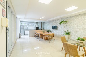 A modern kitchen with a dining area, featuring a large island, built-in appliances, and a flat-screen TV.