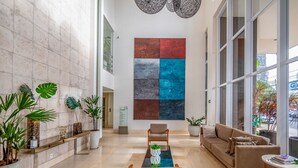 A spacious lobby with a large abstract painting, comfortable seating, and various plants. - Incredible Stay With Pool and gym in Setor Bueno - Dnag (Goiânia)