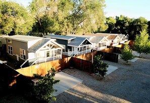 A row of single-story houses with attached porches, a gravel driveway, and a wooden fence.