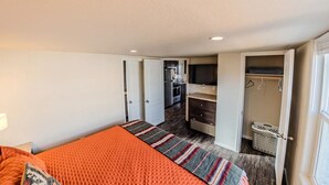 Une chambre compacte comprenant un lit, un petit coin cuisine et un dressing.