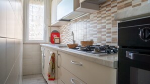 Een keuken met een gasfornuis, een spoelbak en een raam met gordijn.