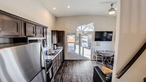 A modern kitchen with dark wooden cabinets, stainless steel appliances, and a large window. - Moab Tiny Home Near Arches | Sleeps 6 | King + Loft | Mill Creek Falls (Moab)