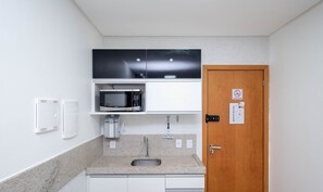 A compact kitchen with a microwave, coffee machine, and a sink. - Apartment Next to Flamboyant Shopping Mall - ESS (Goiânia)