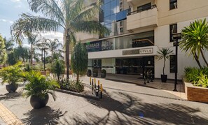 A modern building with a storefront labeled "REBRACE" and "ESSENCIALE STYLE". - Apartment Next to Flamboyant Shopping Mall - ESS (Goiânia)