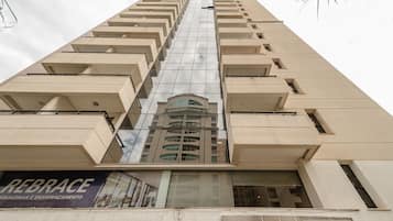 A tall building with a reflective glass facade and a sign reading "REBRACE SQUADRIAS E ENVIDRAÇAMENTO" at the bottom.