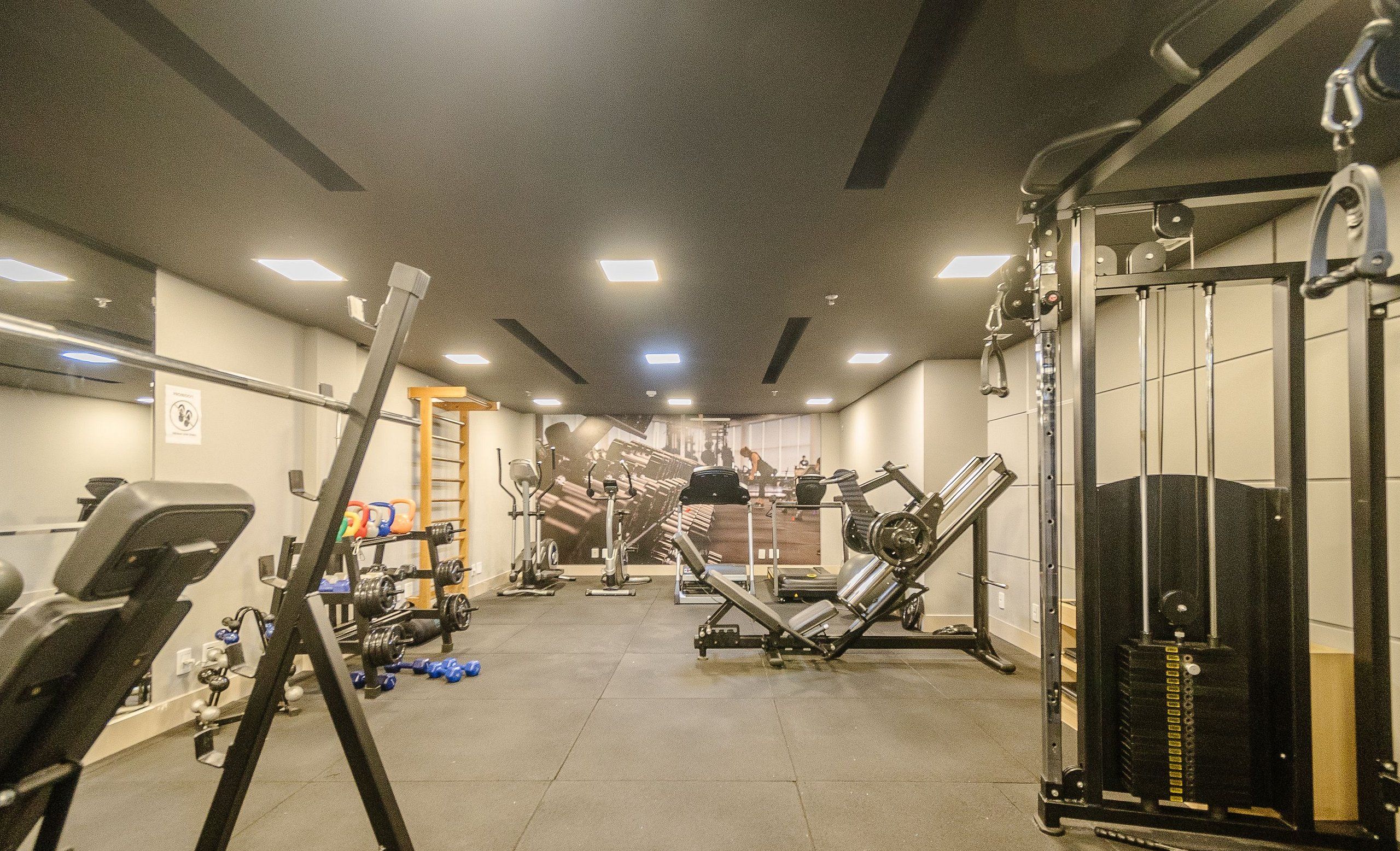 Un gimnasio con diverso equipo de ejercicio, incluyendo cintas de correr, máquinas de pesas y pesas libres.
