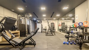 A gym with various exercise equipment, including a bench press, squat rack, and weight bench. - Apartment Next to Flamboyant Shopping Mall - ESS (Goiânia)