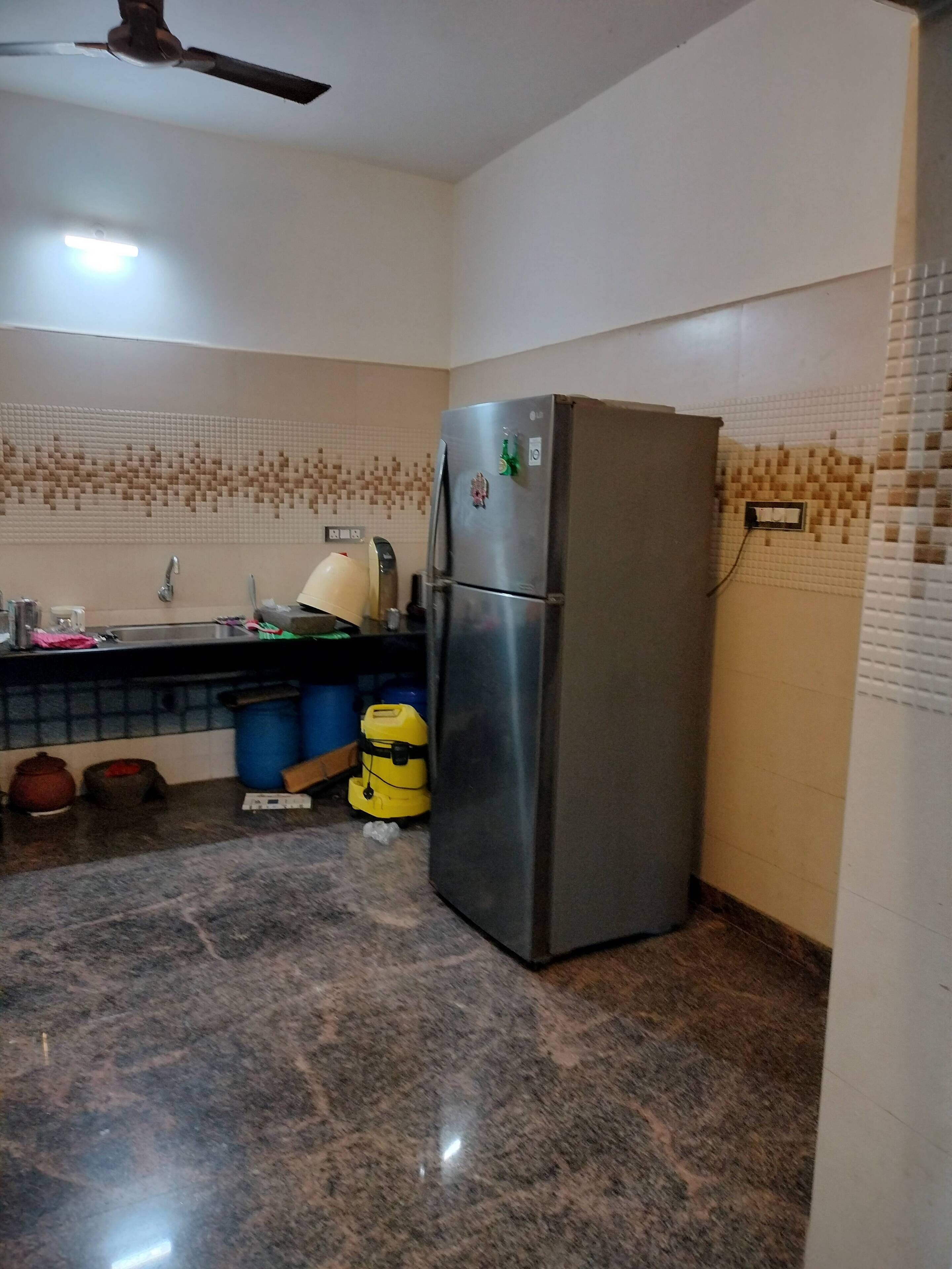 A kitchen with a stainless steel refrigerator, a sink, and a tiled backsplash.