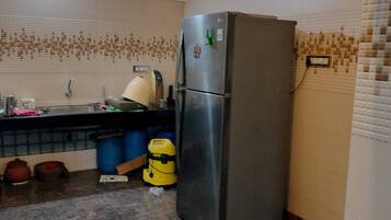 A kitchen with a stainless steel refrigerator, a sink, and a tiled backsplash.