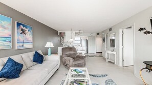 Uma sala de estar moderna com sofá, poltrona, mesa de centro e obra de arte na parede.