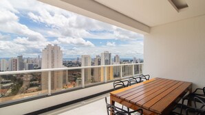 Un balcón con una mesa y sillas de madera, con vista a la ciudad.