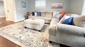 Ein Wohnzimmer mit einem beigefarbenen Sofa, einem passenden Sessel und einem gemusterten Teppich.