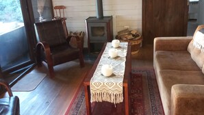 Ein gemütliches Wohnzimmer mit Kamin, einer Couch, einem Holztisch mit Kerzen und einem gemusterten Teppich.