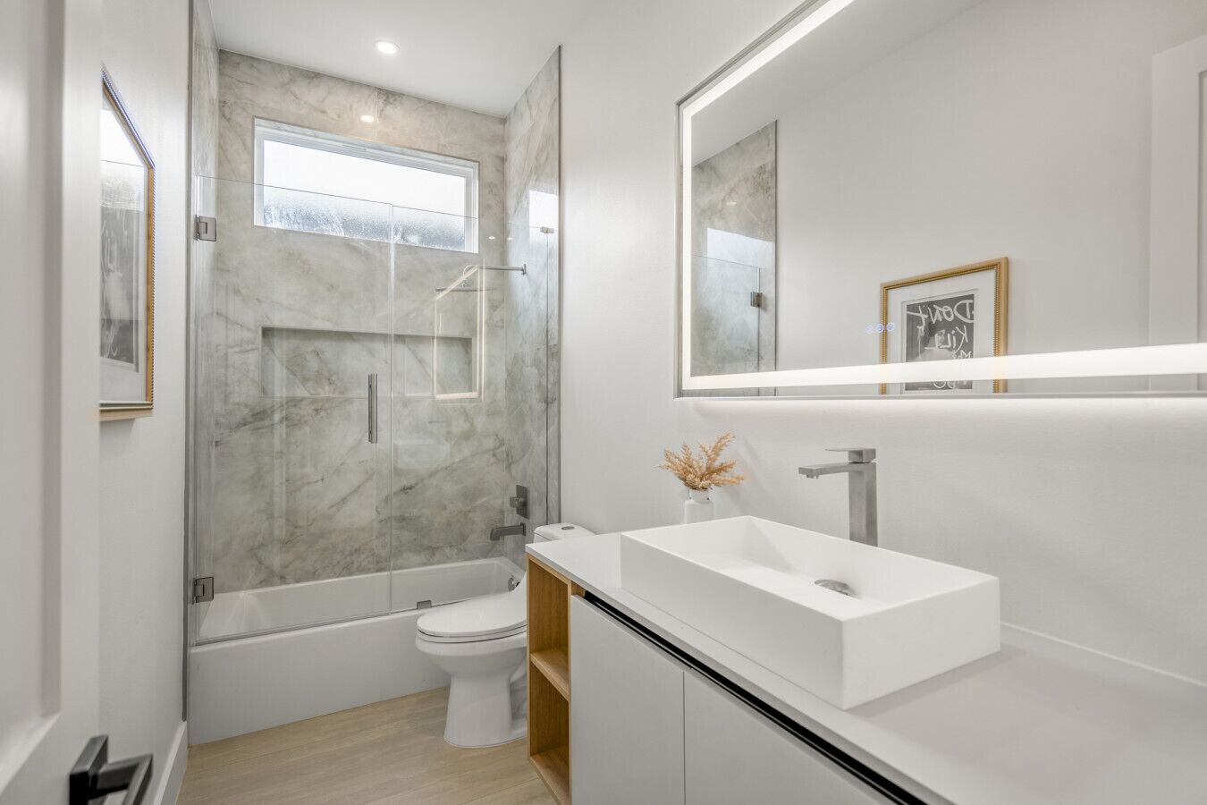 Une salle de bain moderne avec une douche à parois de verre, un lavabo blanc et un grand miroir.