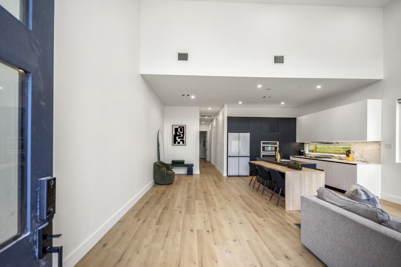 Een moderne keuken met een centraal eiland, een eethoek met stoelen, en een bank.