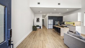 Eine moderne Küche mit einer zentralen Kochinsel, einem Essbereich mit Stühlen und einer Couch.