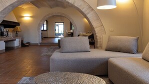 A spacious living area with a stone archway, a sofa set, and a lamp.