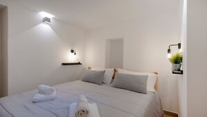 Een moderne slaapkamer met een bed, wandlampen en een kleine potplant.