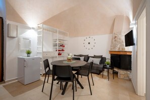 A compact kitchen with a dining area, built-in shelving, a clock, and a stone fireplace.