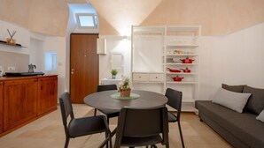 Een kleine woonruimte met een eethoek, een bank, een kitchenette en een inbouwkast.