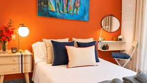 A hotel room with a bed, bedside table, lamp, artwork, and a chair. - CARABEO CASA PEPA (Nerja)