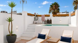 A rooftop terrace with a pool, two lounge chairs, a potted plant, and a staircase leading to an upper level. - CARABEO CASA PEPA (Nerja)
