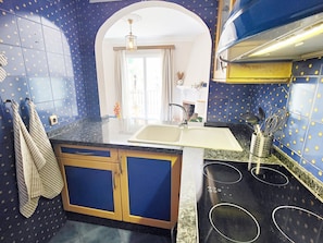 A kitchen with blue tiled walls, a sink, and a stove.