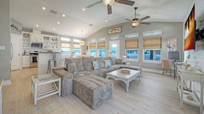 A spacious living area with a large sectional sofa, a dining table, and a kitchen with white cabinetry. - Sleeps 24 2 Homes w/ Beach Boardwalk Access & Deck Views Steps to the Beach (Port Aransas)