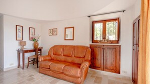 Uma sala de estar com sofá de couro, aparador de madeira e quadros nas paredes.