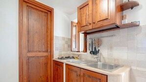 A kitchen with wooden cabinets, a stainless steel sink, and a tiled backsplash.