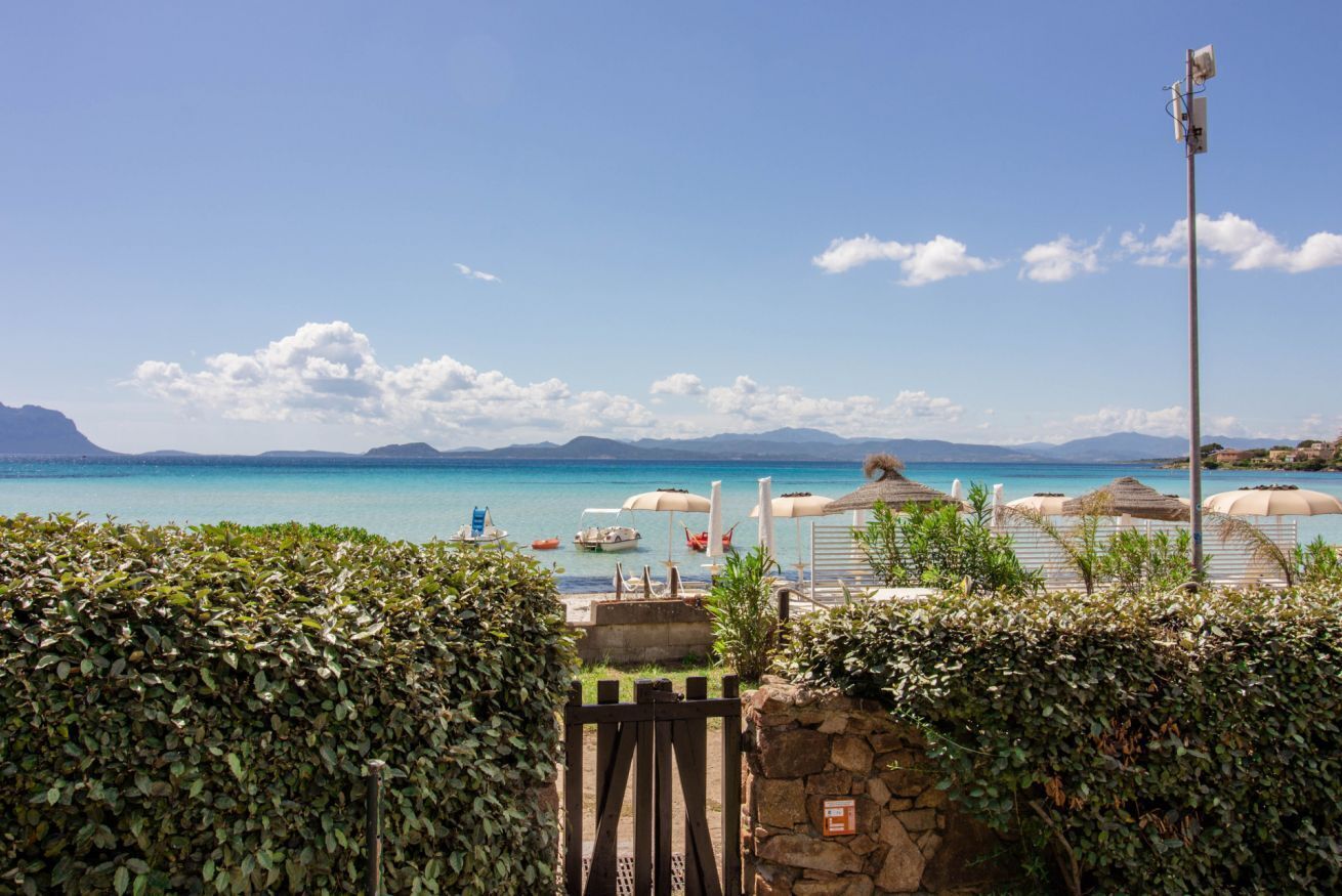 A coastal view with a clear sky, a stone wall, and umbrellas.