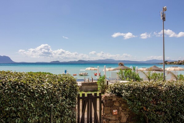 A coastal view with a clear sky, a stone wall, and umbrellas.