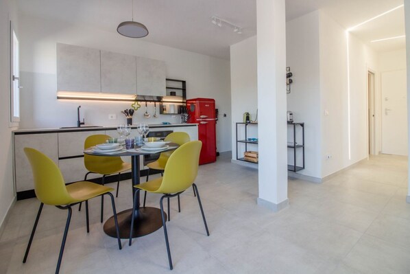 A modern kitchen with a dining area, featuring a central island, yellow chairs, and a red refrigerator.