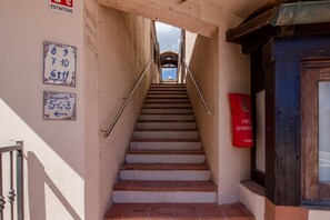 A staircase leading to a building entrance with a fire extinguisher and numbered signs on the wall.