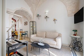 A living room with a sofa, a coffee table, a TV, and a staircase leading to another room.