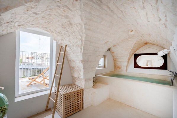 A bathroom with a bathtub, a window, and a view of a building outside.