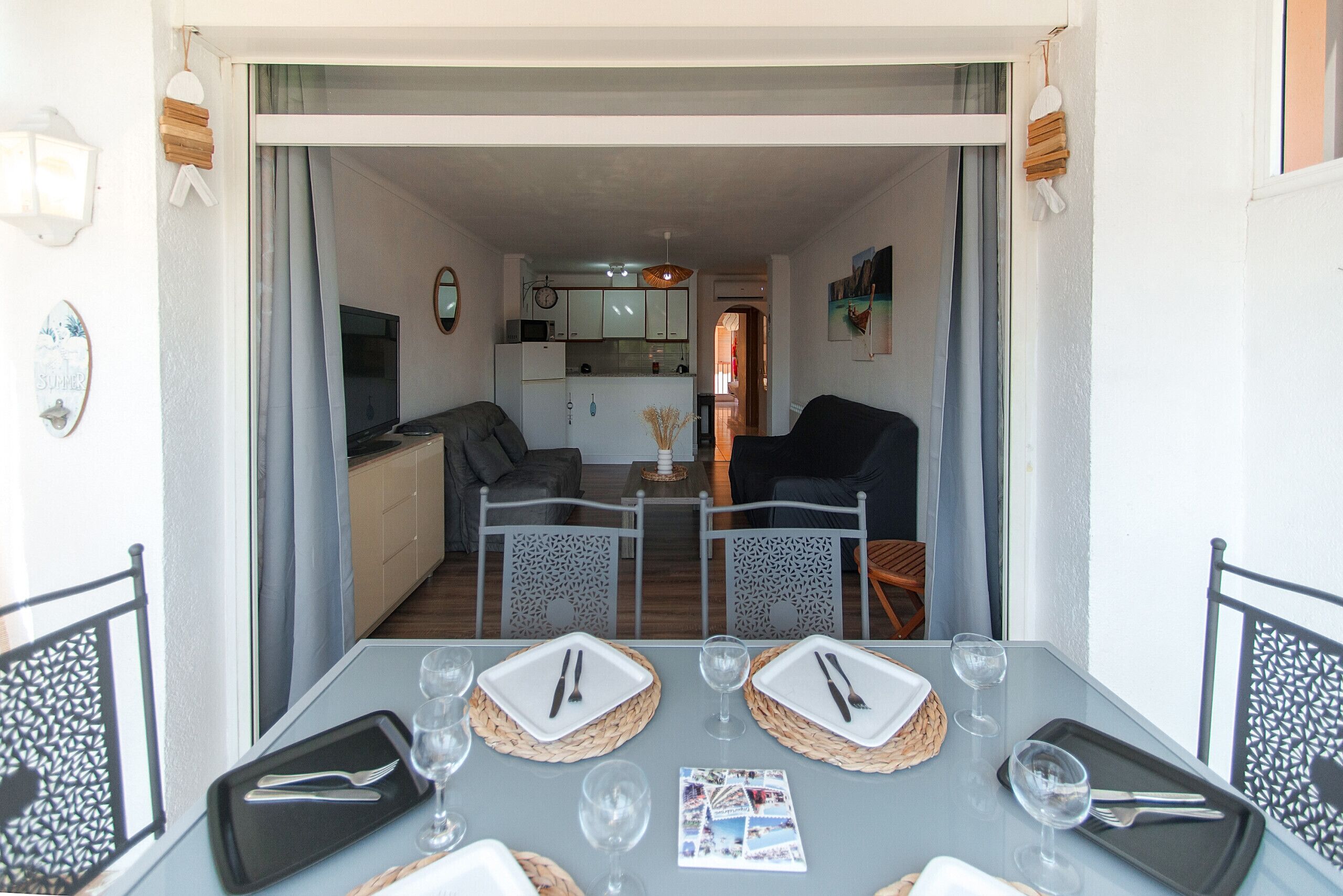 A dining area with a table set for two, two chairs, and a view into the kitchen.