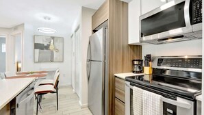 A modern kitchen with a built-in oven, microwave, and refrigerator. There is a dining area with a table and chairs. - Chic 2BR Edgewater Condo w/ Views + Balcony (Miami)