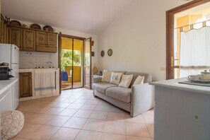Une cuisine compacte avec un canapé, une petite table et une vue sur l’extérieur grâce à une porte ouverte.