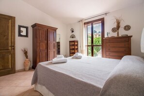 Une chambre à coucher avec un lit, une armoire en bois et une fenêtre donnant sur un beau paysage.