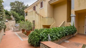 A building with a stone pathway, potted plants, and a staircase leading to an upper level. - GuestHost - Cozy 55 sqm apartment, ideal for 3 people, located on the first floor of a building without a lift.The property is located in San Pantaleo, a charming village in the hinterland of the Costa Smeralda, which combines the authentic charm of loca (San Pantaleo)